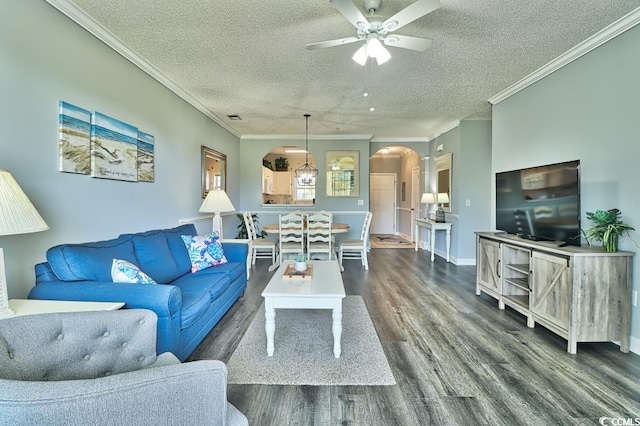 living room featuring dark hardwood / wood-style flooring, a textured ceiling, ceiling fan, and ornamental molding