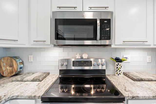 kitchen with decorative backsplash, stainless steel appliances, white cabinetry, and light stone counters