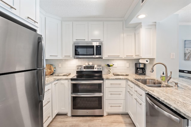 kitchen featuring white cabinets, appliances with stainless steel finishes, decorative backsplash, and sink