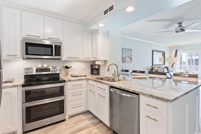 kitchen with kitchen peninsula, stainless steel appliances, white cabinetry, and sink