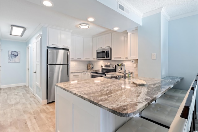 kitchen with stainless steel appliances, white cabinetry, and sink