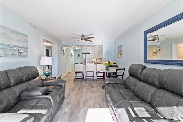 living room featuring light wood-type flooring and crown molding