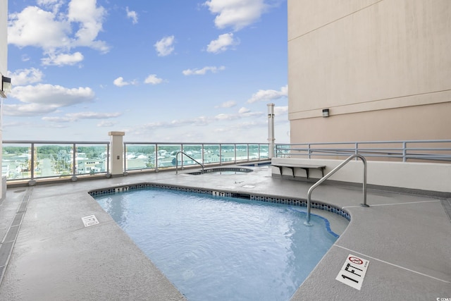 view of swimming pool with a water view and a hot tub