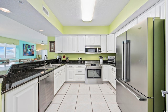 kitchen featuring white cabinets, sink, ceiling fan, dark stone countertops, and stainless steel appliances