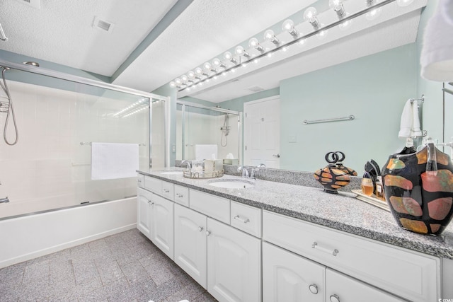 bathroom with vanity, bath / shower combo with glass door, and a textured ceiling