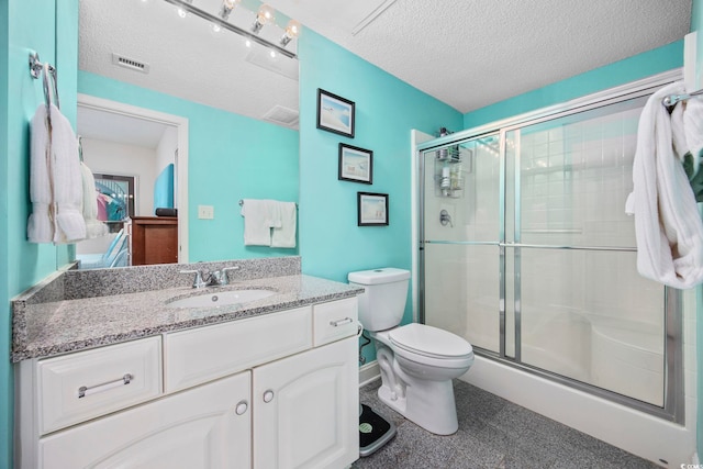 bathroom featuring vanity, a textured ceiling, and a shower with shower door