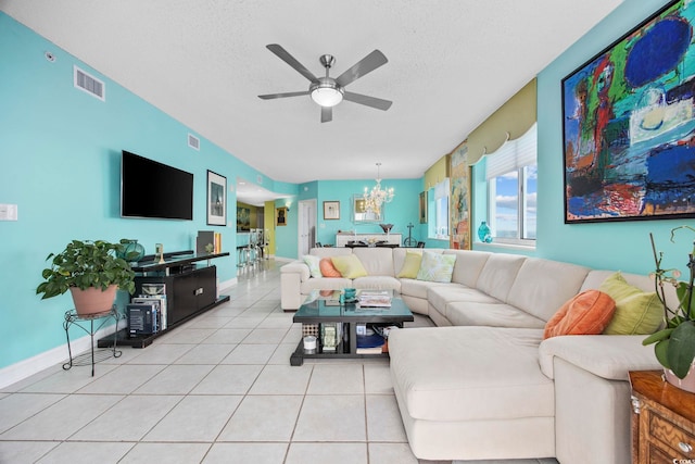 living room with ceiling fan with notable chandelier, light tile patterned flooring, and a textured ceiling