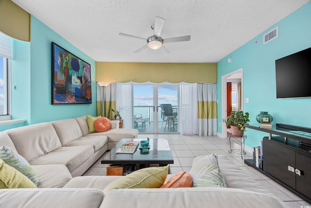 living room with ceiling fan, light tile patterned floors, and a textured ceiling