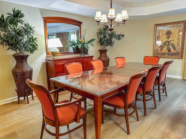 dining area featuring crown molding, light hardwood / wood-style floors, and a notable chandelier