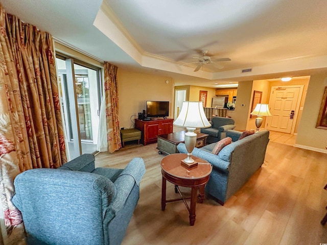 living room featuring a tray ceiling, ceiling fan, and light hardwood / wood-style floors