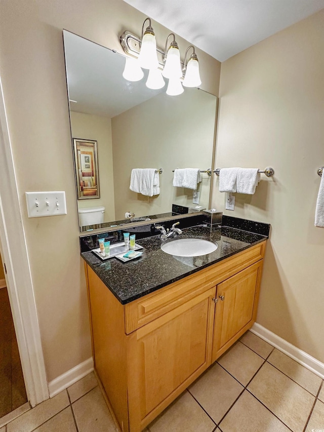 bathroom with toilet, vanity, and tile patterned floors