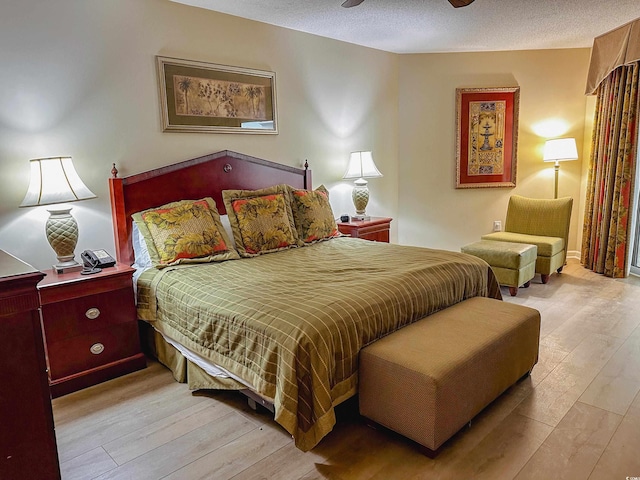 bedroom with ceiling fan, a textured ceiling, and light hardwood / wood-style flooring