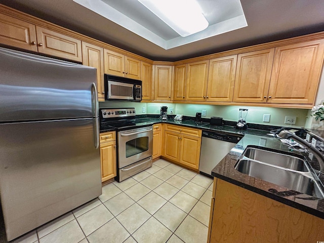 kitchen featuring a tray ceiling, sink, light tile patterned flooring, and appliances with stainless steel finishes