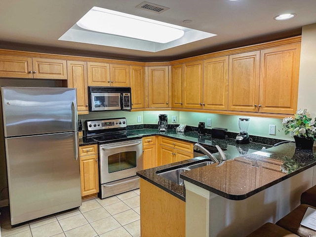 kitchen featuring kitchen peninsula, stainless steel appliances, and dark stone counters