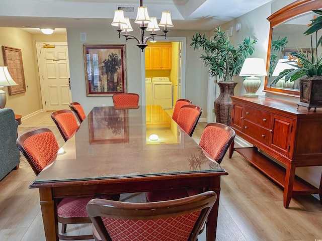 dining space featuring a chandelier, light wood-type flooring, and washing machine and dryer