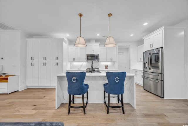 kitchen featuring white cabinetry, a center island with sink, stainless steel appliances, and decorative light fixtures