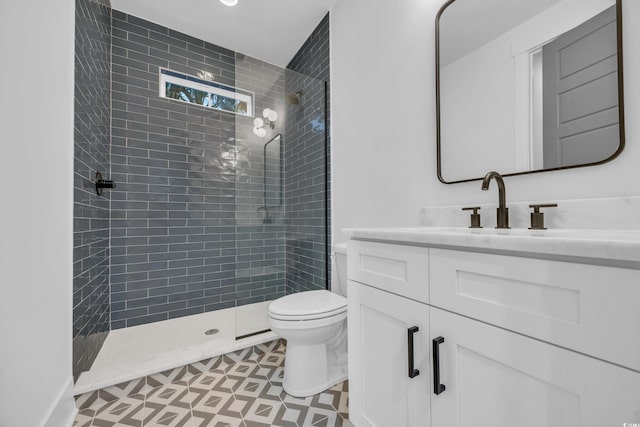 bathroom with tiled shower, tile patterned floors, vanity, and toilet