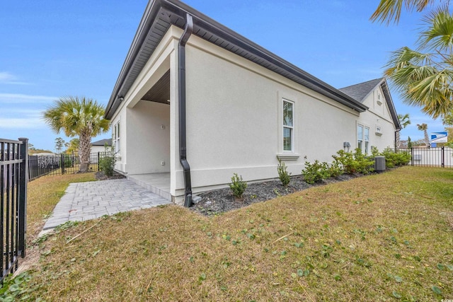 view of property exterior with central AC unit, a yard, and a patio