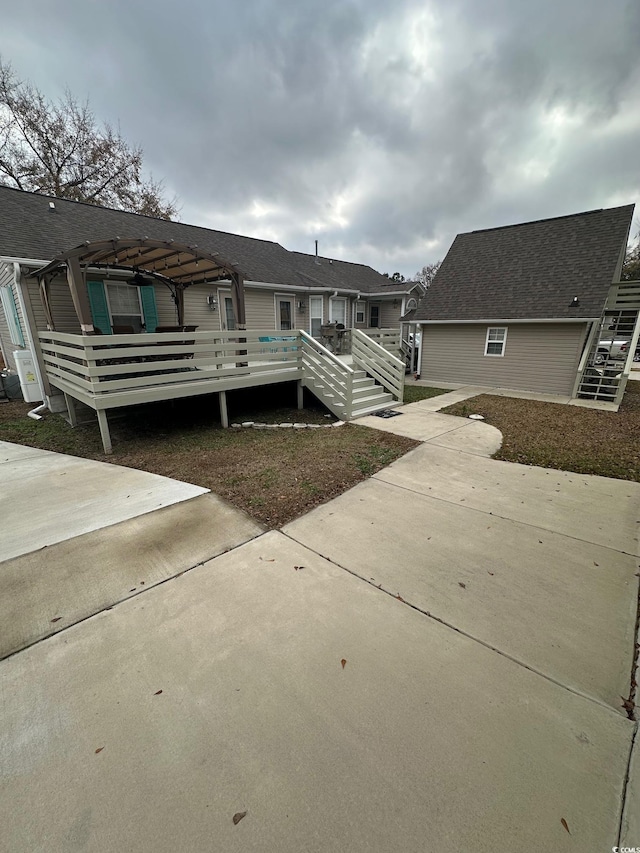 rear view of house featuring a pergola and a deck