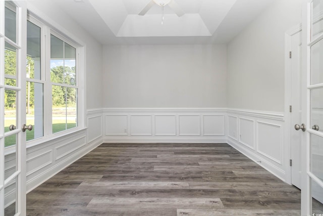 empty room with a raised ceiling, ceiling fan, and dark wood-type flooring