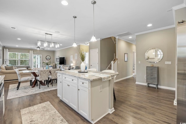 kitchen with white cabinetry, ceiling fan, light stone counters, pendant lighting, and a kitchen island