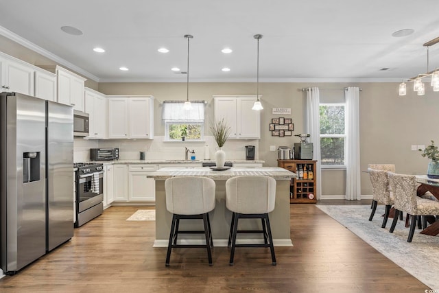 kitchen with white cabinetry, light hardwood / wood-style flooring, pendant lighting, a kitchen island, and appliances with stainless steel finishes