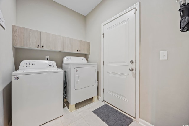 clothes washing area with cabinets, independent washer and dryer, and light tile patterned floors