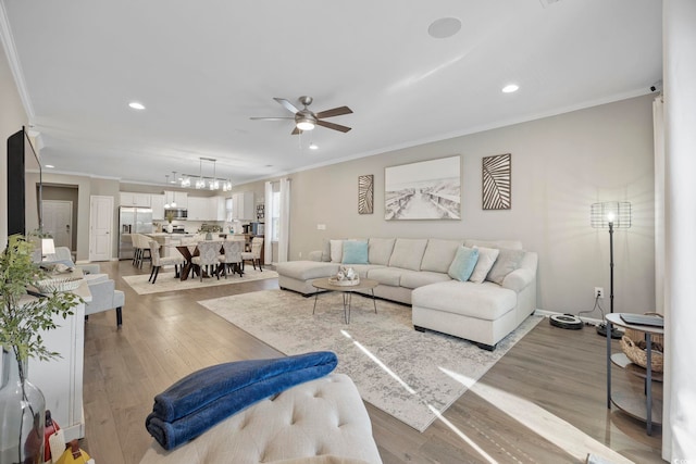 living room featuring ceiling fan, light hardwood / wood-style floors, and ornamental molding