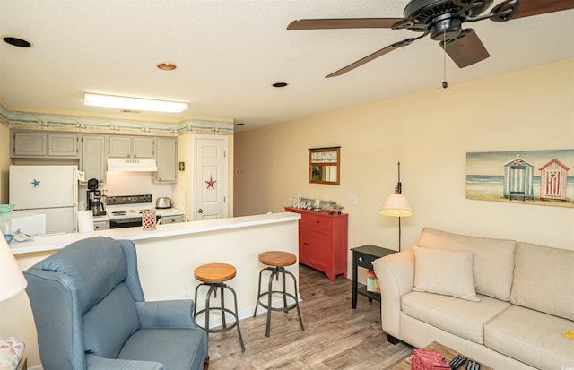 kitchen featuring a kitchen breakfast bar, light wood-type flooring, pendant lighting, white fridge, and range with electric stovetop