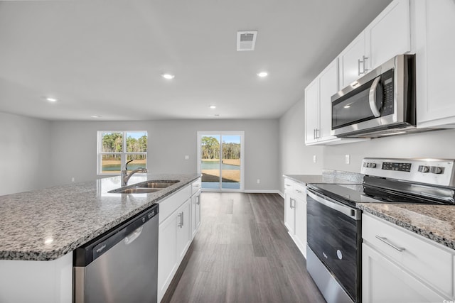 kitchen with white cabinetry, sink, stainless steel appliances, dark hardwood / wood-style flooring, and a center island with sink