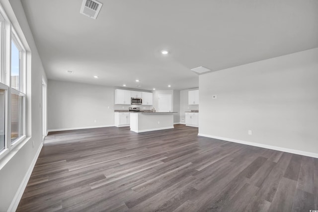 unfurnished living room featuring dark hardwood / wood-style flooring and a wealth of natural light