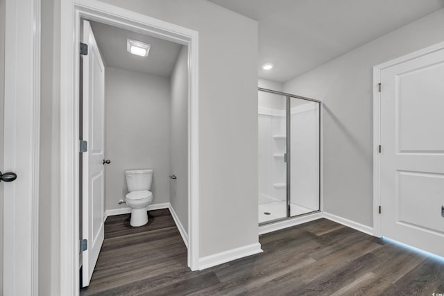 bathroom featuring wood-type flooring, a shower with shower door, and toilet