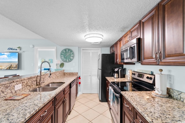 kitchen featuring light stone counters, a textured ceiling, stainless steel appliances, sink, and light tile patterned flooring