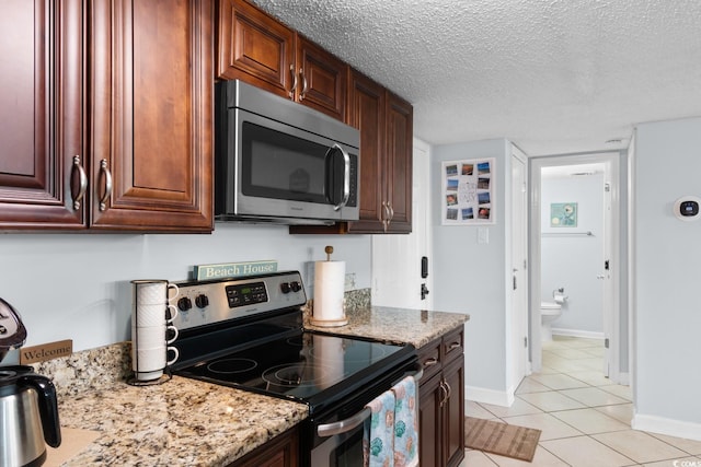 kitchen with light stone countertops, light tile patterned floors, stainless steel appliances, and a textured ceiling