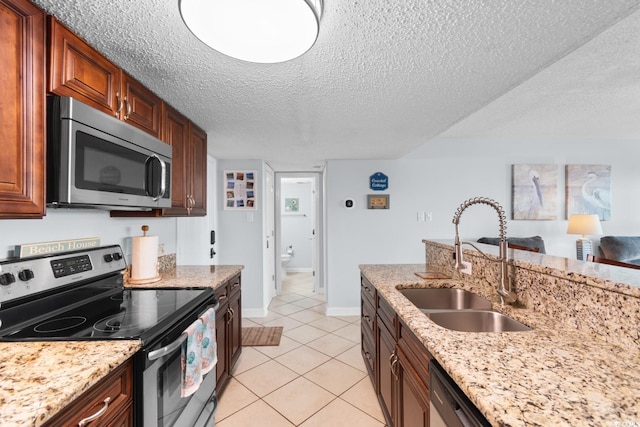 kitchen featuring appliances with stainless steel finishes, light stone counters, light tile patterned floors, and sink