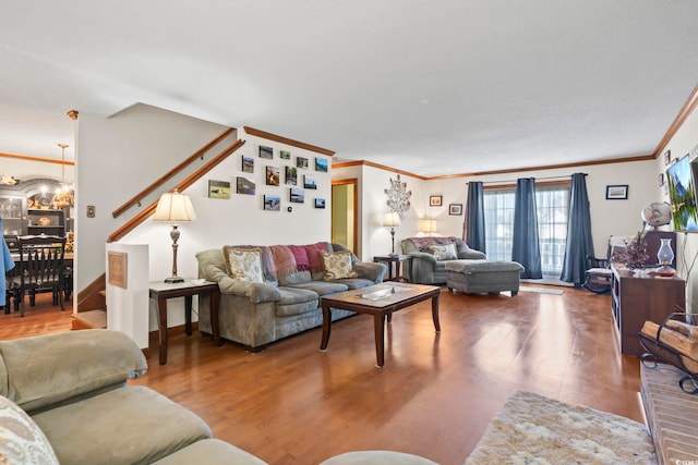 living room with wood-type flooring, crown molding, and a notable chandelier