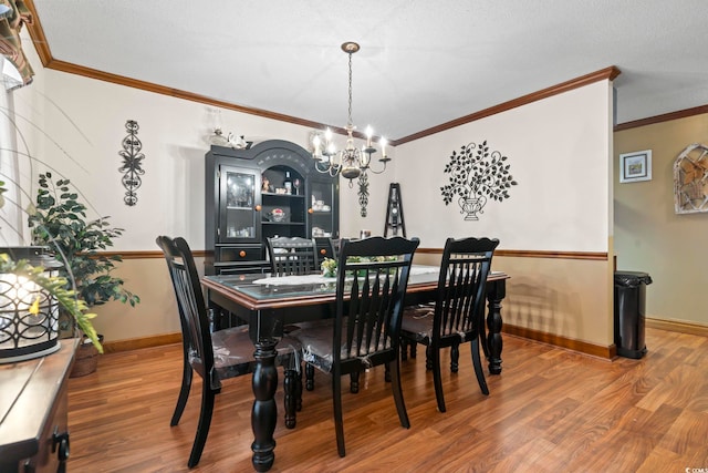 dining space with wood-type flooring, ornamental molding, and an inviting chandelier