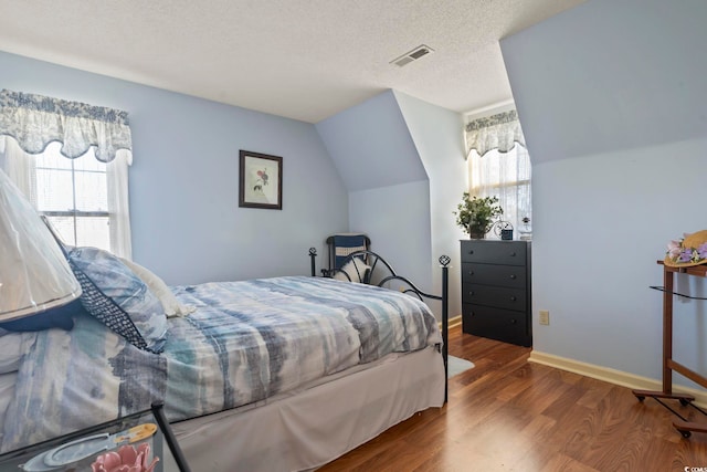 702 Plantation Dr, Surfside Beach, SC 29575 - bedroom with multiple windows, wood finished floors, a textured ceiling, lofted ceiling, and baseboards