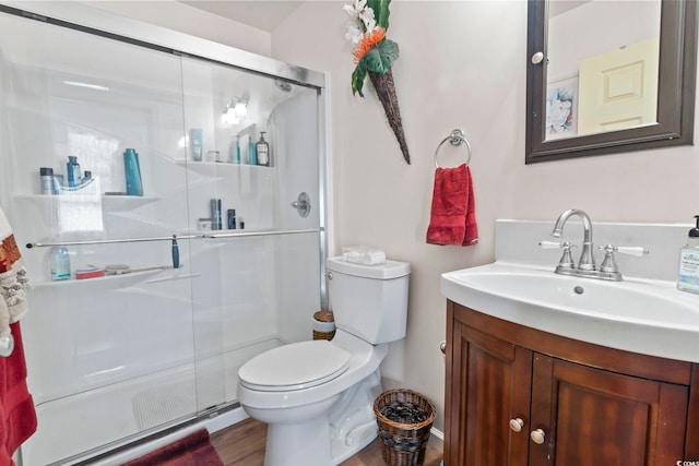 bathroom with vanity, hardwood / wood-style flooring, toilet, and a shower with shower door