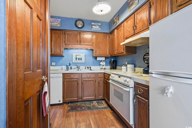 702 Plantation Dr, Surfside Beach, SC 29575 - kitchen with white appliances, under cabinet range hood, light countertops, wood finished floors, and brown cabinets