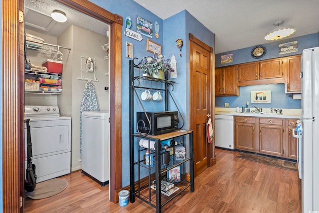 702 Plantation Dr, Surfside Beach, SC 29575 - kitchen with dishwasher, washing machine and clothes dryer, light wood-style flooring, black microwave, and light countertops