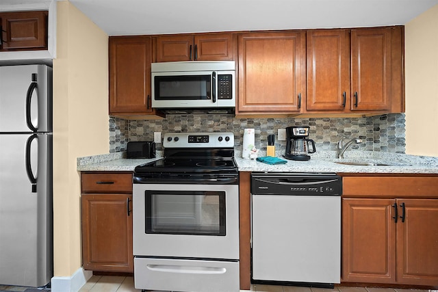 kitchen with sink, light stone counters, stainless steel appliances, and tasteful backsplash