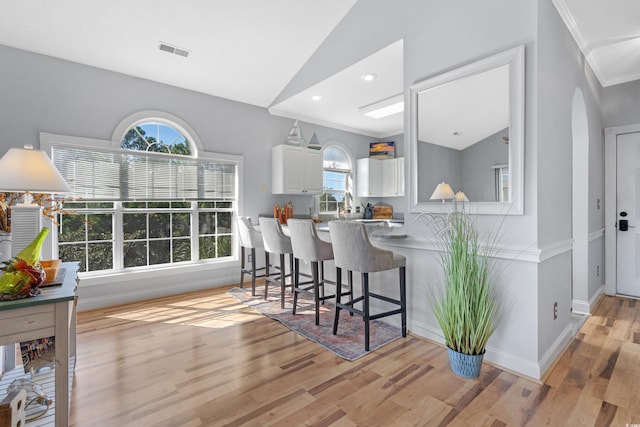 kitchen featuring lofted ceiling, light wood-type flooring, white cabinetry, and kitchen peninsula