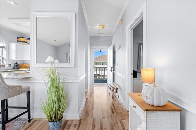 corridor with light hardwood / wood-style floors and crown molding