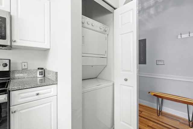 laundry room with wood-type flooring, stacked washer and dryer, and electric panel