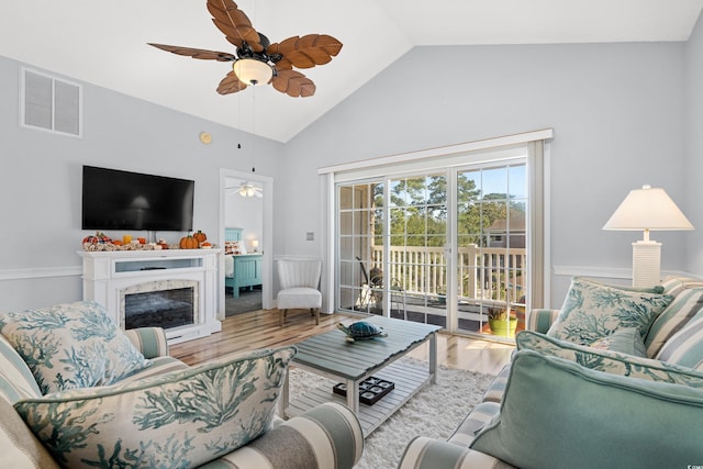 living room featuring hardwood / wood-style flooring, ceiling fan, a high end fireplace, and vaulted ceiling