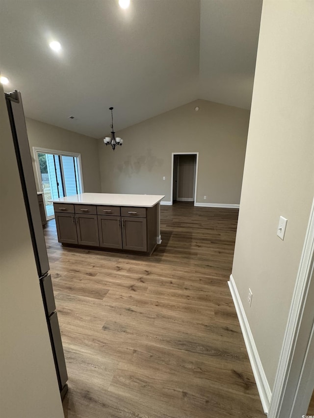 kitchen featuring stainless steel refrigerator, a chandelier, pendant lighting, lofted ceiling, and wood-type flooring