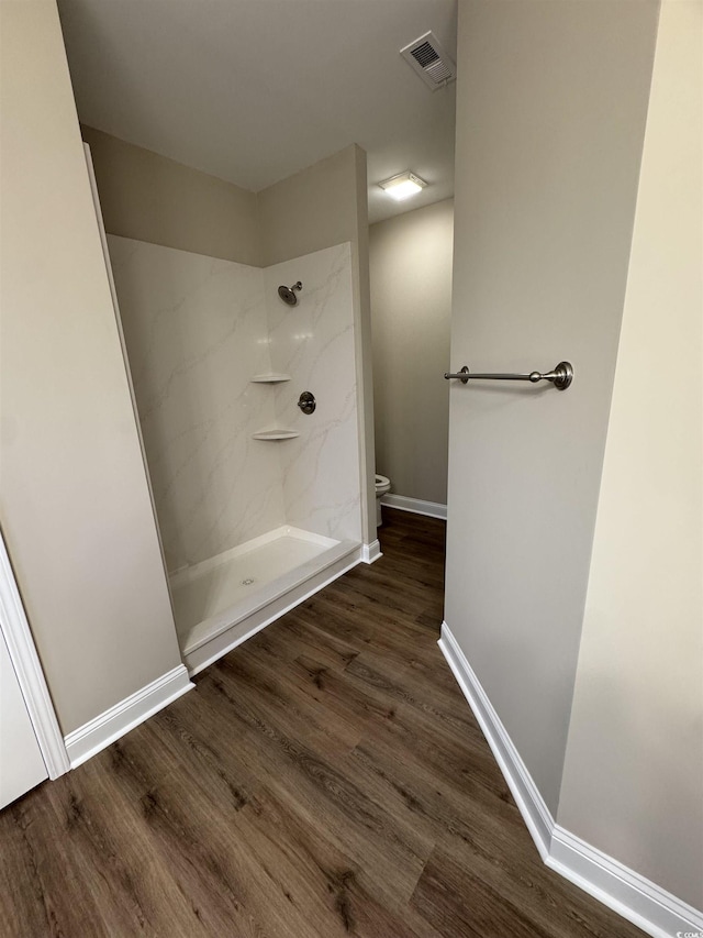 bathroom featuring hardwood / wood-style flooring, toilet, and walk in shower