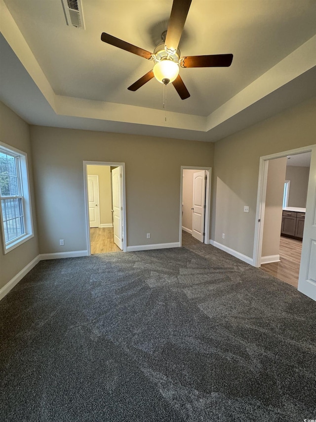 unfurnished bedroom with carpet, ceiling fan, and a tray ceiling