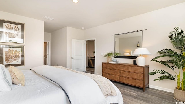 bedroom with connected bathroom and dark hardwood / wood-style flooring